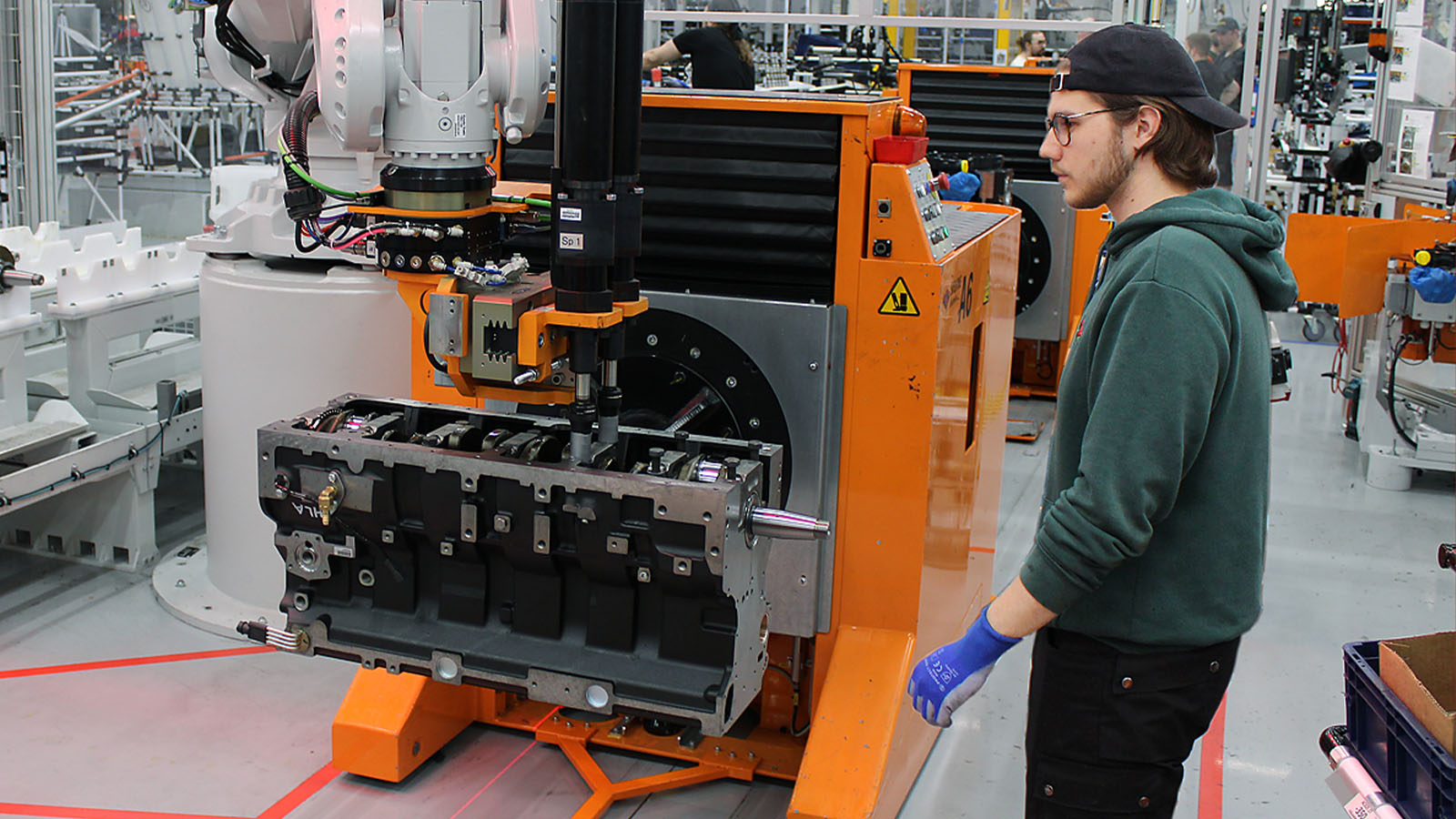 Asentaja Julius Salmela asentaa kuusisylinteriseen moottoriin kampiakselia yhteistyössä teollisuusrobotin kanssa.
